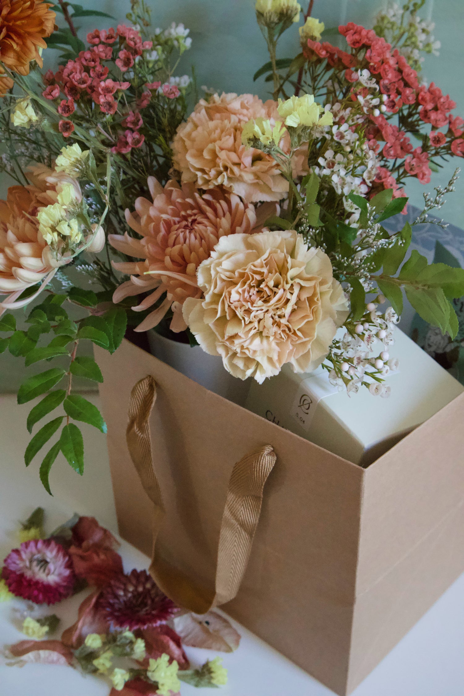 Floral arrangement in a brown paper bag with a light background - gift box 